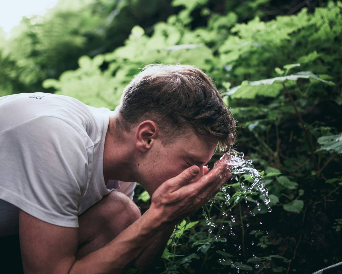 face cleaning routine for men showing a man gently washing his face with a gentle cleanser in the bathroom